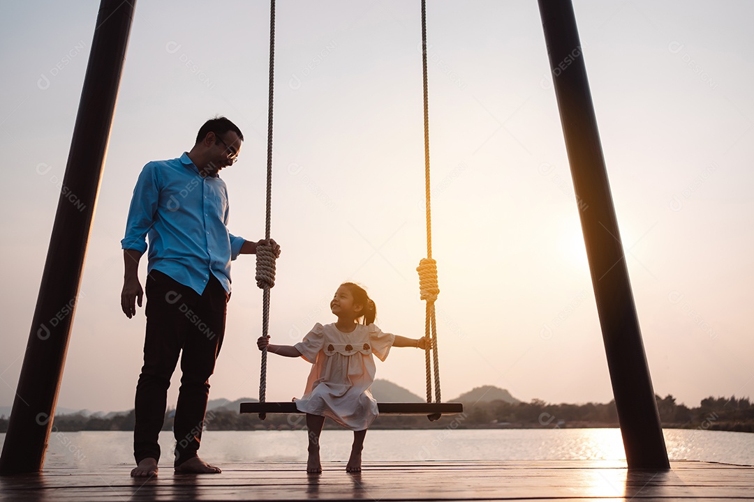 Família feliz curtindo com balanço no parque ao pôr do sol ao ar livre na natureza