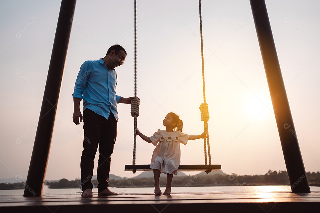 Família feliz curtindo com balanço no parque ao pôr do sol ao ar livre na natureza