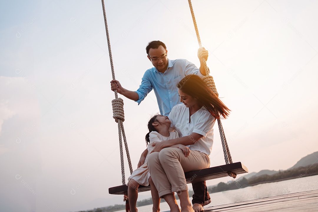 Família feliz curtindo com balanço no parque ao pôr do sol ao ar livre na natureza