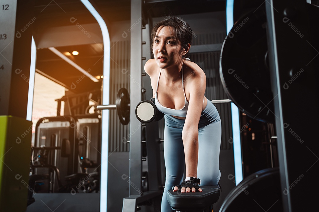 Mulheres malhando com pesos de treinamento levantando halteres no ginásio de fitness.
