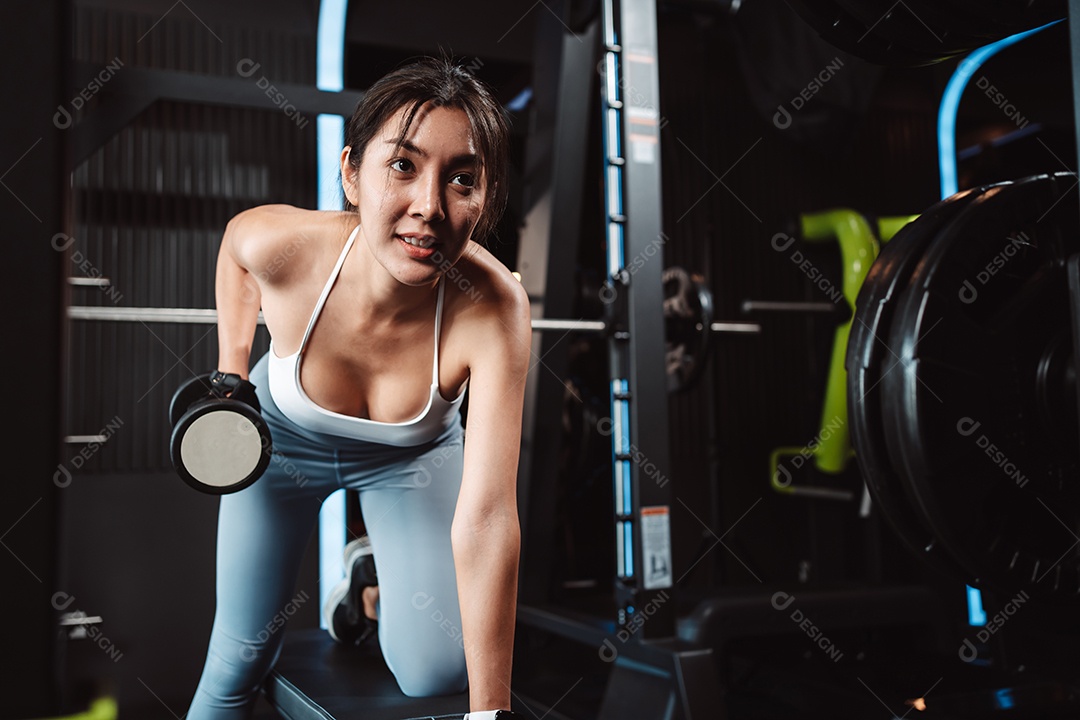 Mulheres malhando com pesos de treinamento levantando halteres no ginásio de fitness.