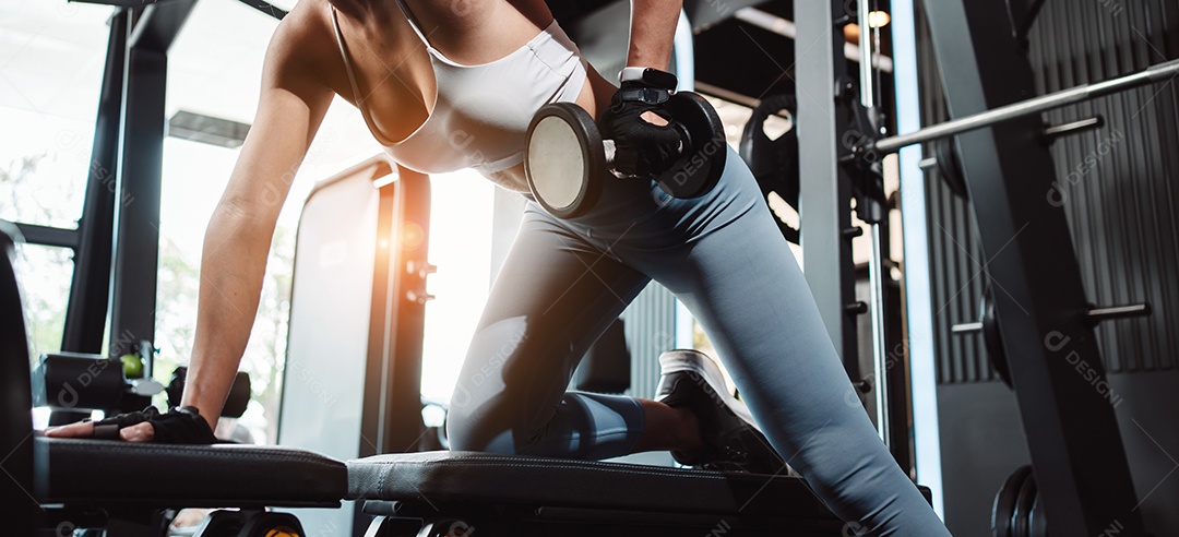 Mulheres malhando com pesos de treinamento levantando halteres no ginásio de fitness.