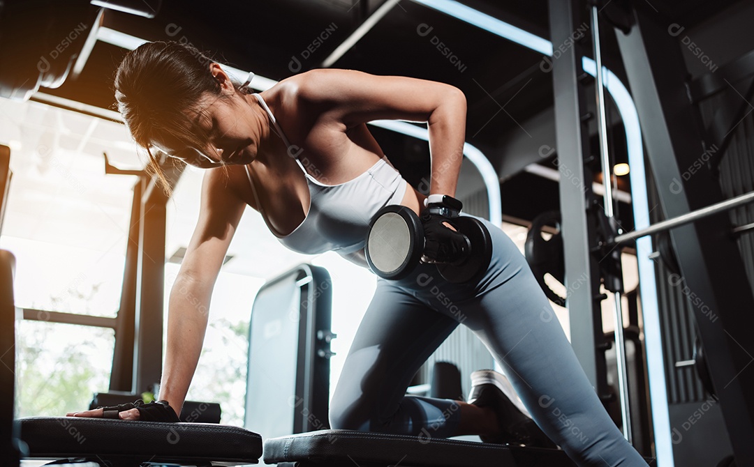 Mulheres malhando com pesos de treinamento levantando halteres no ginásio de fitness.