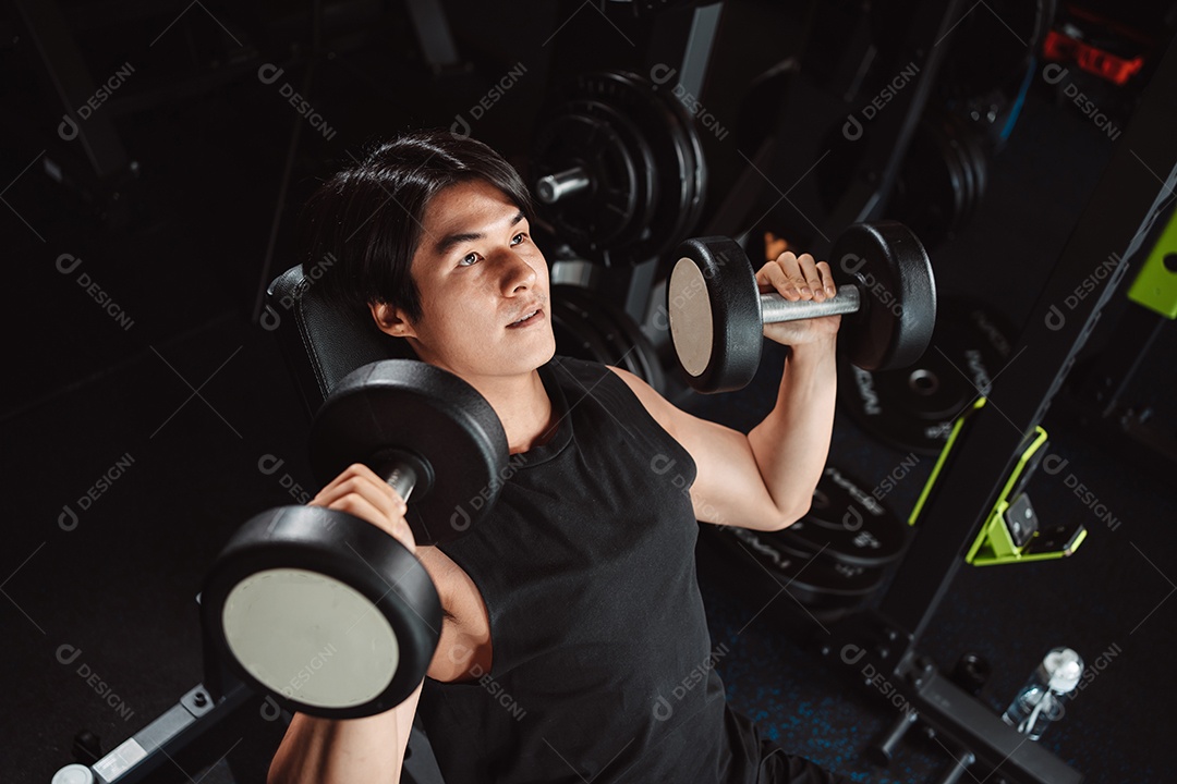 Macho malhando fisiculturista com pesos de halteres no fisiculturista gym.man fazendo exercícios com halteres.