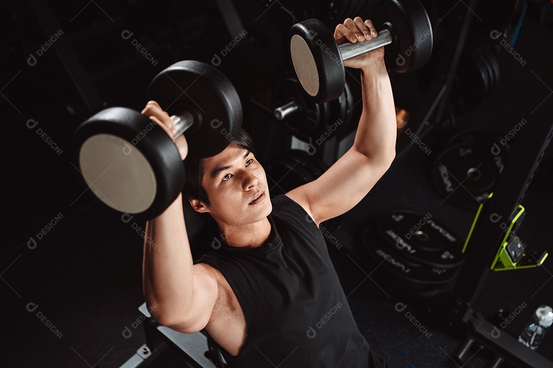 Macho malhando fisiculturista com pesos de halteres no fisiculturista gym.man fazendo exercícios com halteres.