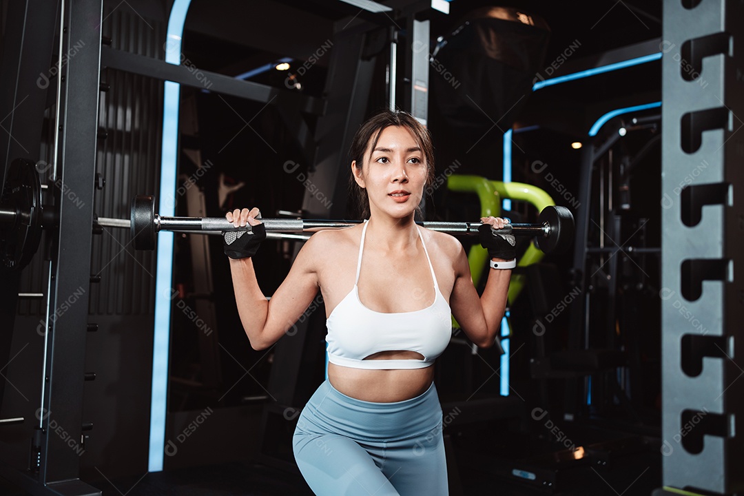 Mulher malhando fisiculturista com pesos de barra na academia.
