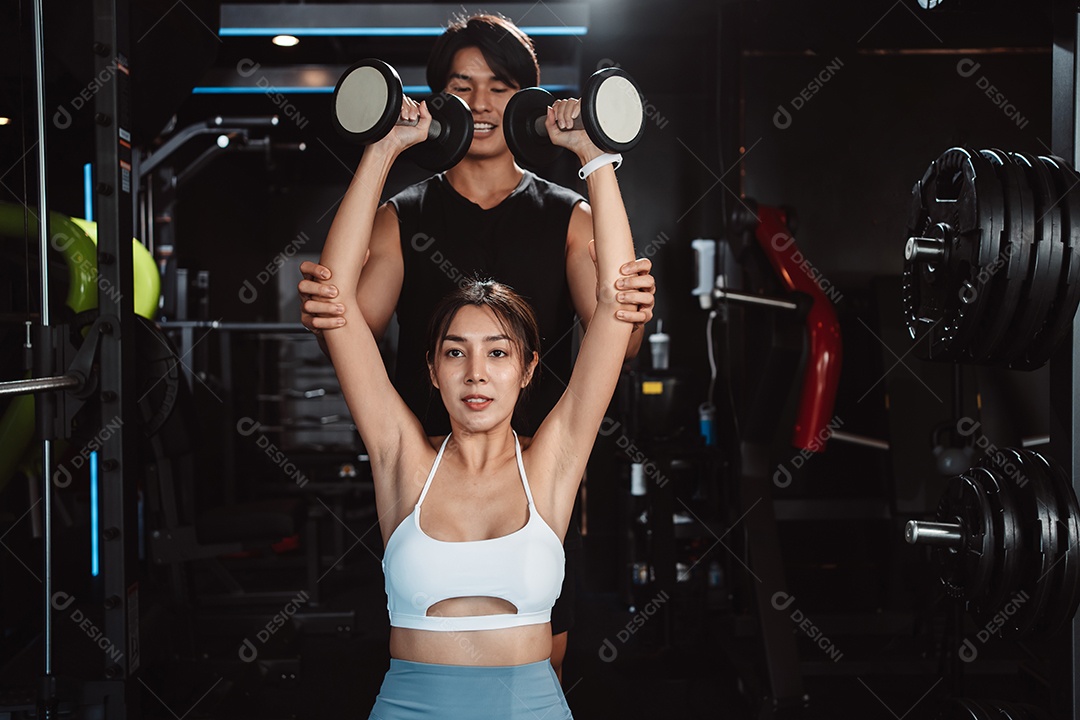 Mulher malhando fisiculturista com assistência de treinamento para suportar pesos na academia.