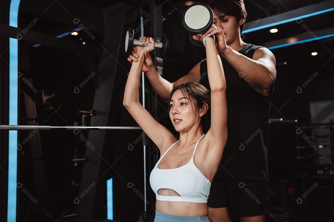 Mulher malhando fisiculturista com assistência de treinamento para suportar pesos na academia.