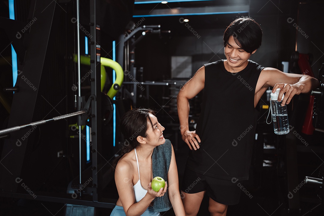 Mulher malhando fisiculturista com assistência de treinamento para suportar pesos na academia.