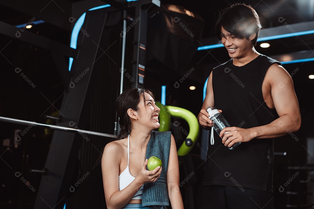 Mulher malhando fisiculturista com assistência de treinamento para suportar pesos na academia.