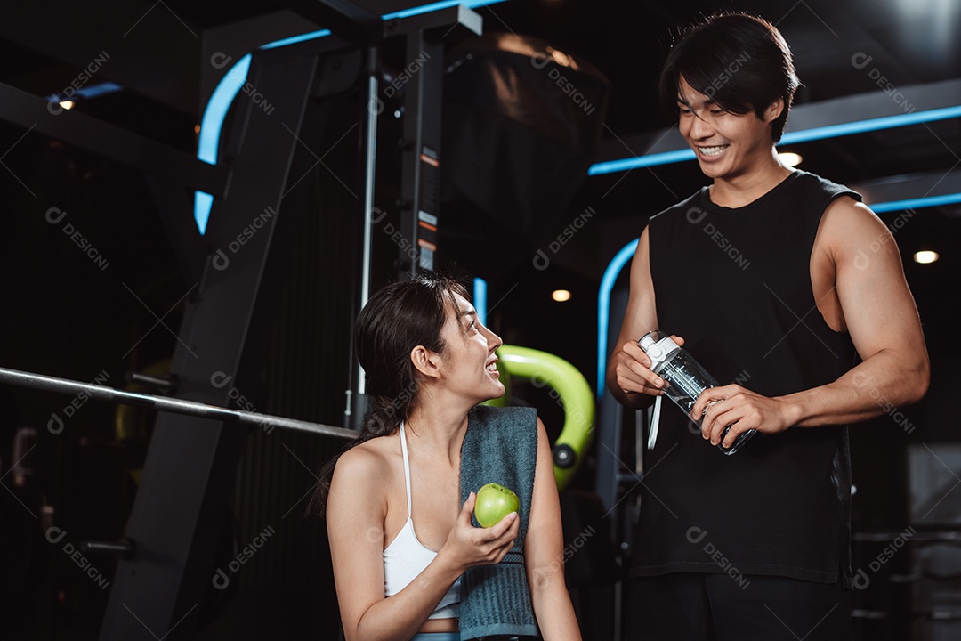 Mulher malhando fisiculturista com assistência de treinamento para suportar pesos na academia.