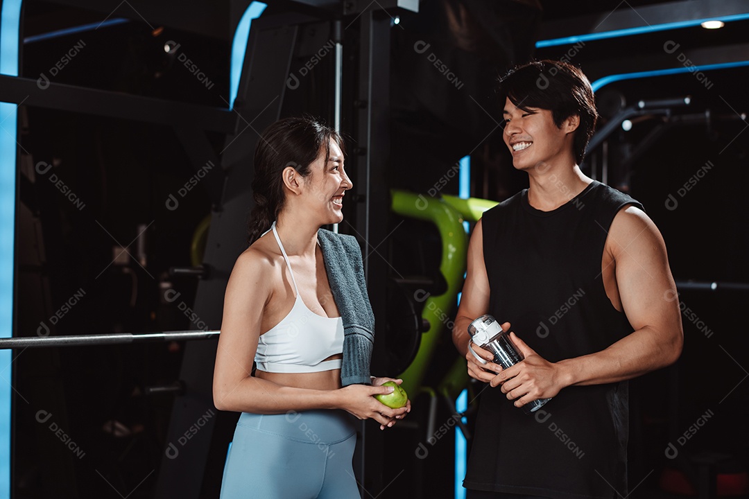 Mulher malhando fisiculturista com assistência de treinamento para suportar pesos na academia.