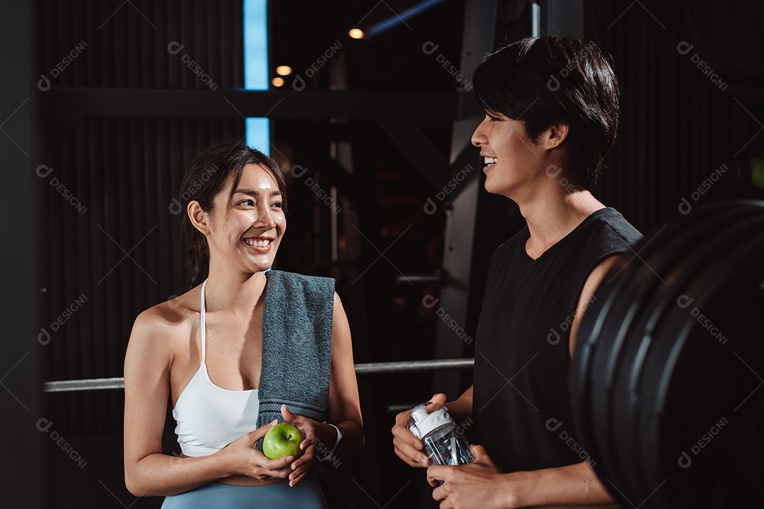 Mulher malhando fisiculturista com assistência de treinamento para suportar pesos na academia.