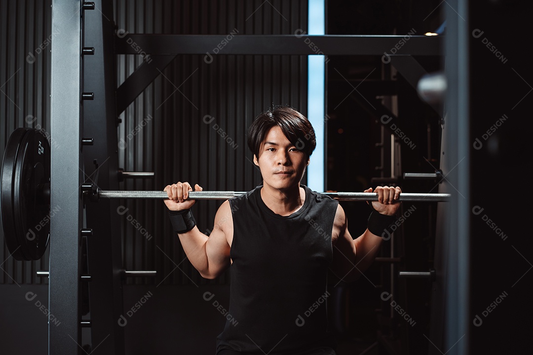 Homem malhando fisiculturista com pesos de barra no ginásio. fisiculturista fazendo exercícios com barra.