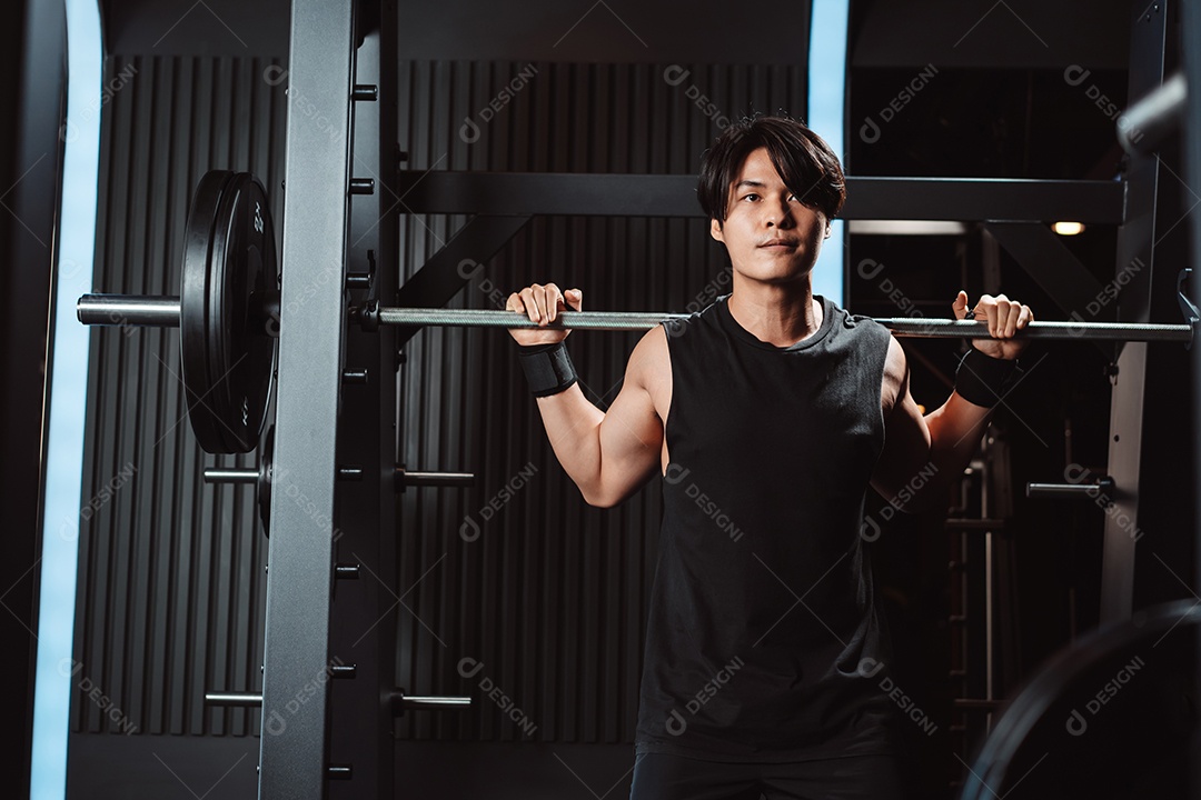 Homem malhando fisiculturista com pesos de barra no ginásio. fisiculturista fazendo exercícios com barra.