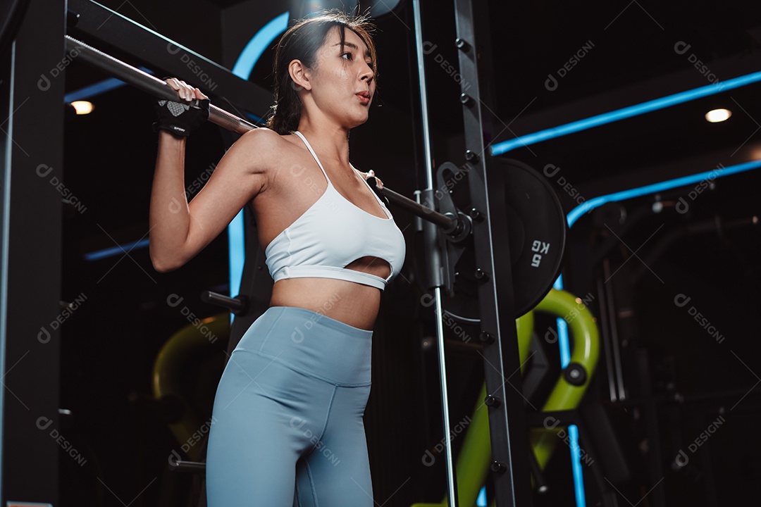 Mulher malhando fisiculturista com pesos de barra na academia.