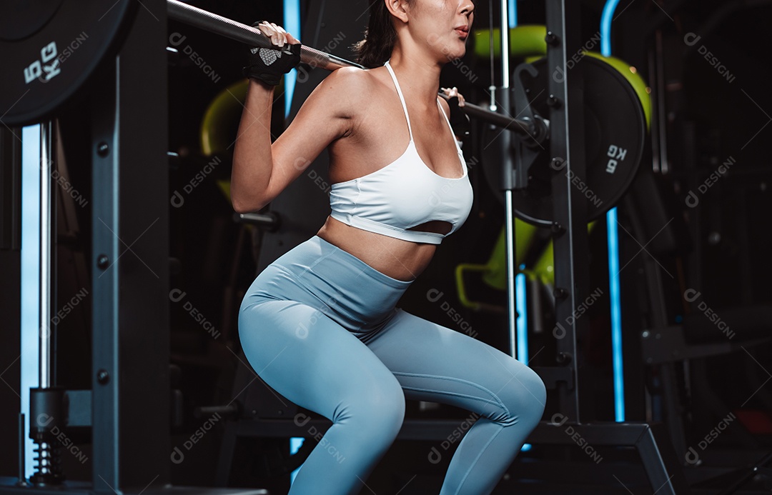 Mulher malhando fisiculturista com pesos de barra na academia.