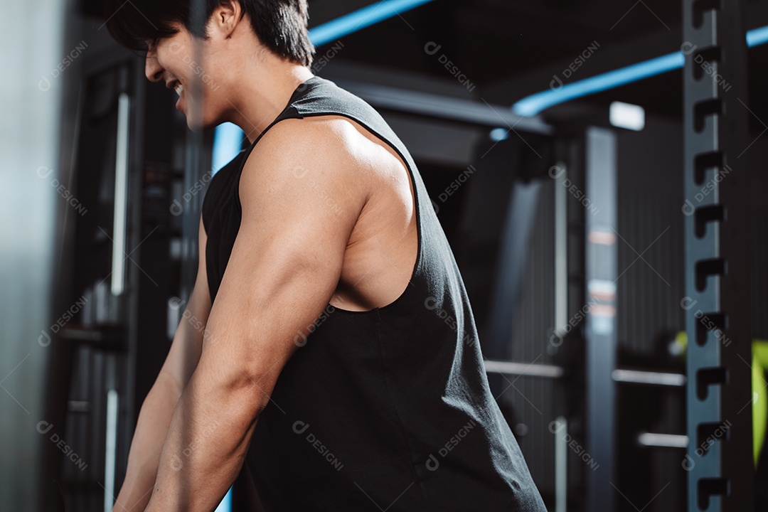 Homem malhando com máquina de treinamento de pesos levantando halteres no ginásio de fitness.