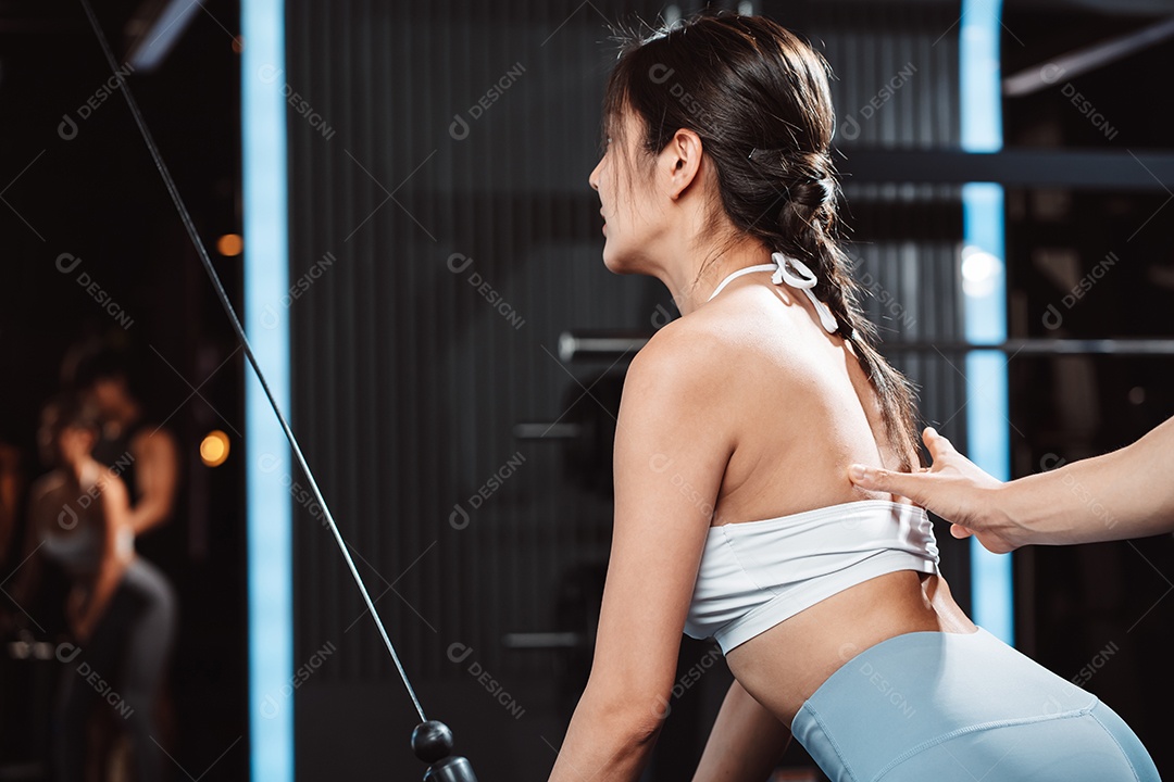 Mulher malhando fisiculturista com assistência de treinamento para suportar pesos na academia.