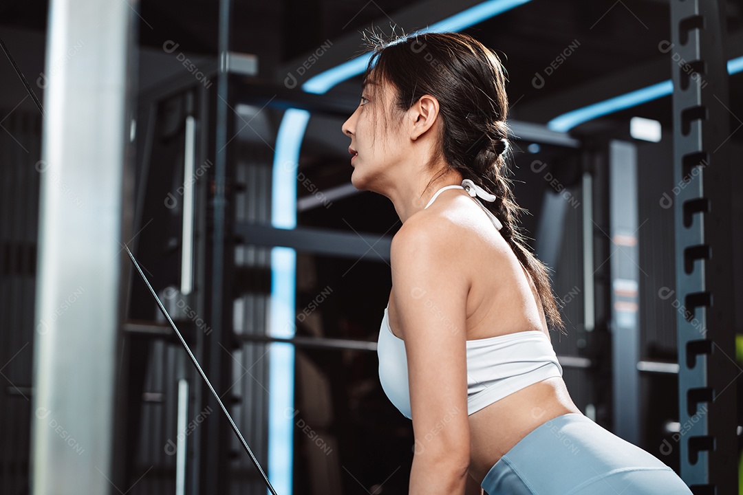 Mulheres malhando com máquina de treinamento de pesos levantando halteres na academia de ginástica.