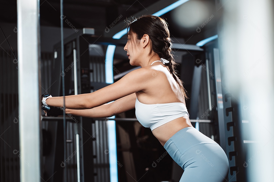 Mulheres malhando com máquina de treinamento de pesos levantando halteres na academia de ginástica.