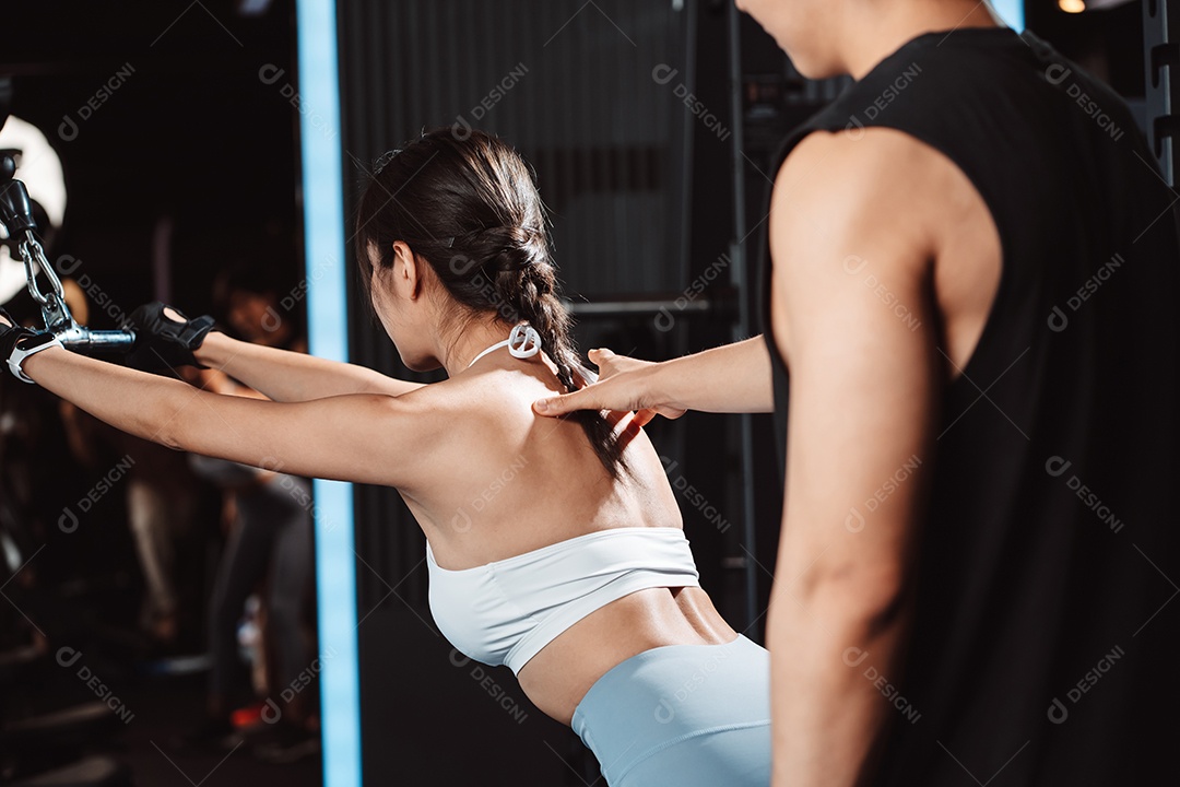 Mulher malhando fisiculturista com assistência de treinamento para suportar pesos na academia.