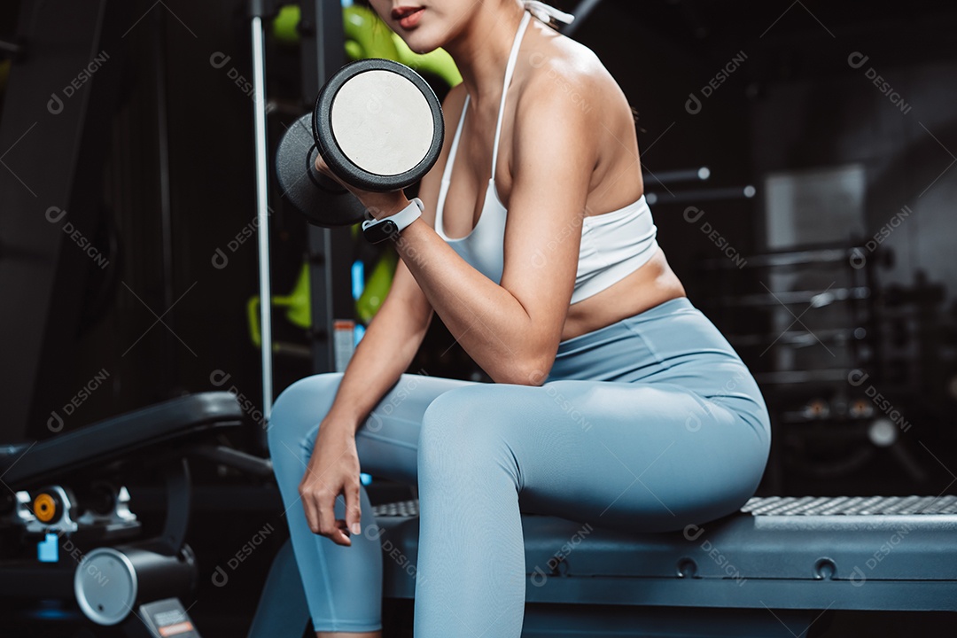 Mulher malhando fisiculturista com pesos de halteres na Academia.