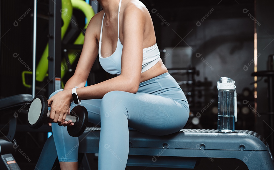 Mulher malhando fisiculturista com pesos de halteres na Academia.
