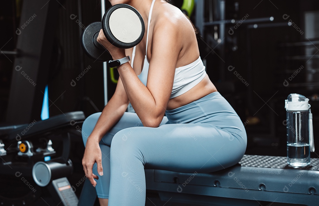 Mulher malhando fisiculturista com pesos de halteres na Academia.