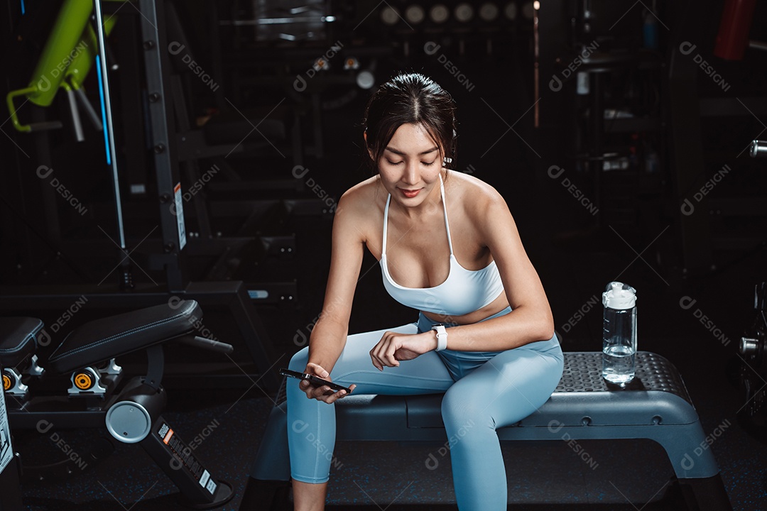 A mulher verificando o tempo e usando o smartphone no exercício