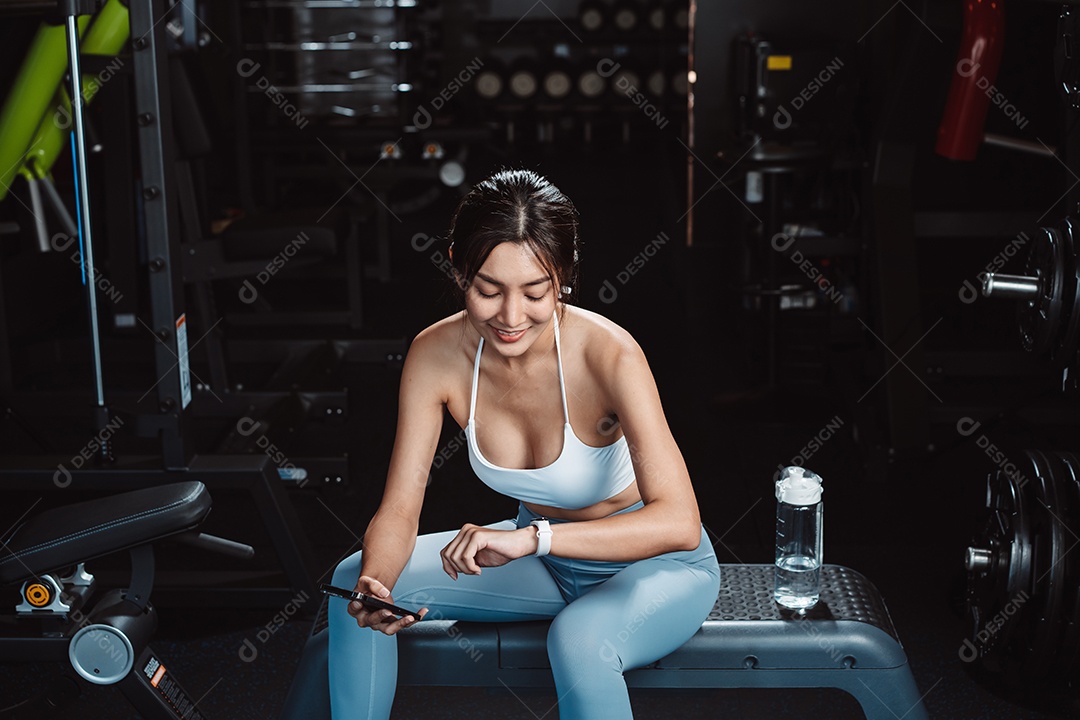 A mulher verificando o tempo e usando o smartphone no exercício
