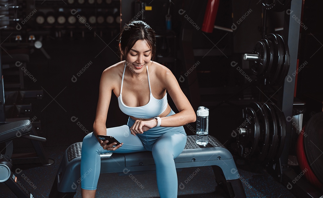 A mulher verificando o tempo e usando o smartphone no exercício