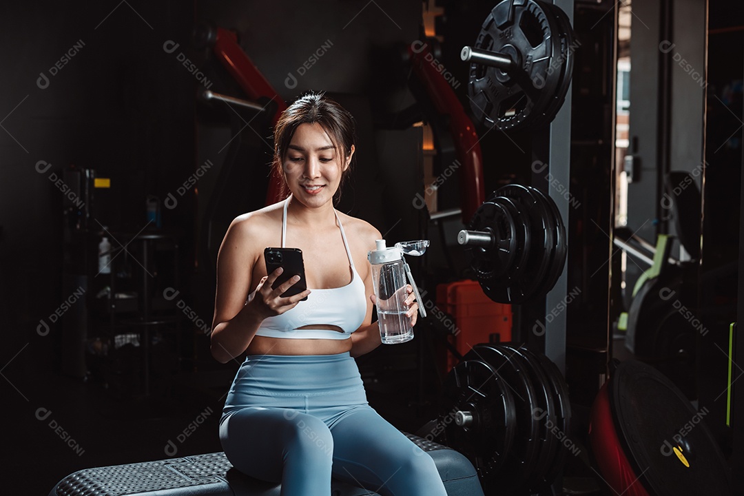 A mulher verificando o tempo e usando o smartphone no treino