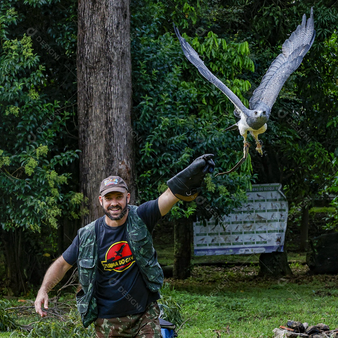 Homem jovem sobre campo verde com seu animal de estimação águia