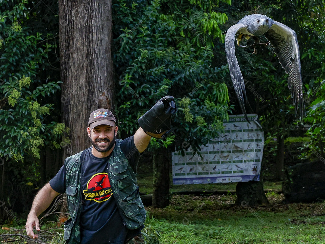 Homem jovem sobre campo verde com seu animal de estimação águia