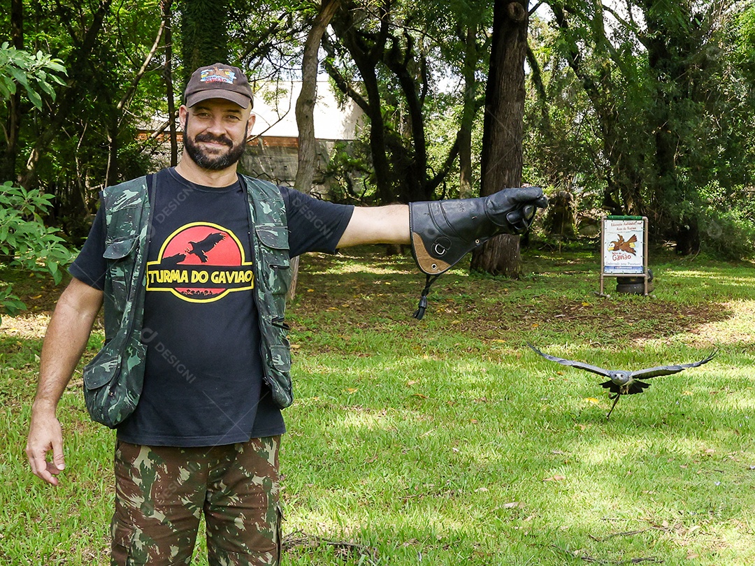 Homem jovem sobre campo verde com seu animal de estimação águia