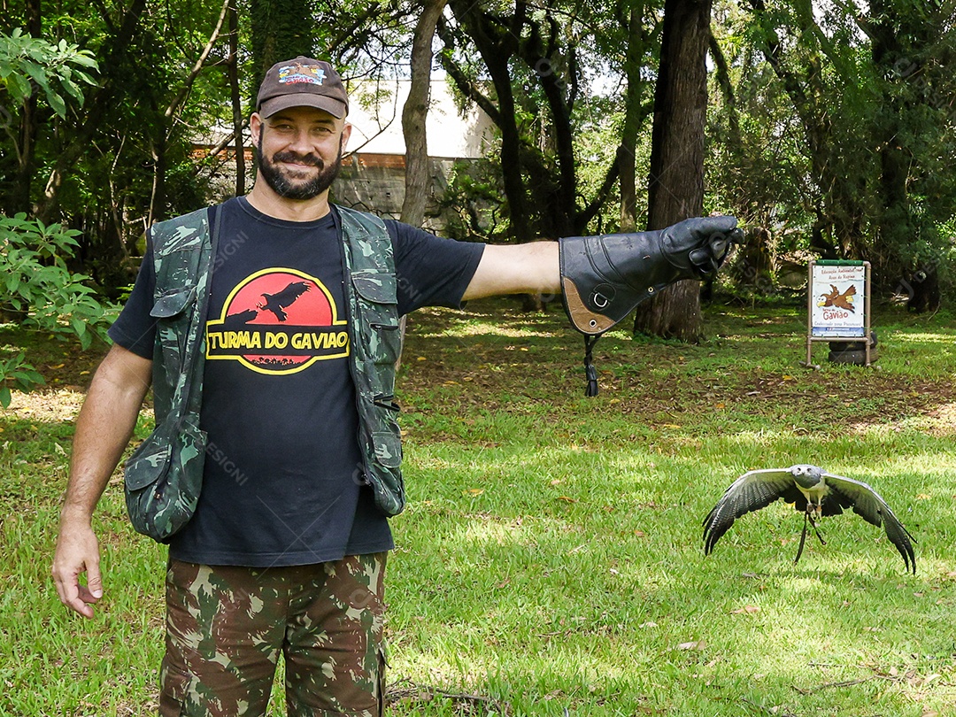 Homem jovem sobre campo verde com seu animal de estimação águia