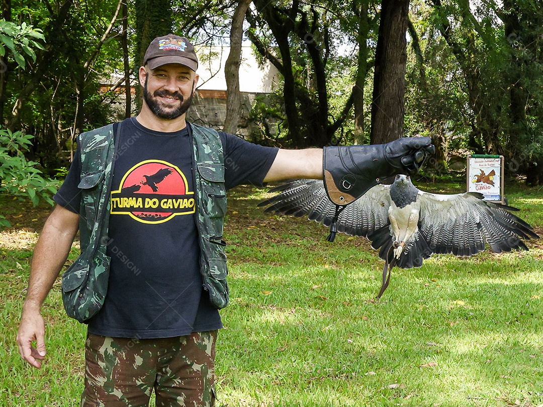 Homem jovem sobre campo verde com seu animal de estimação águia