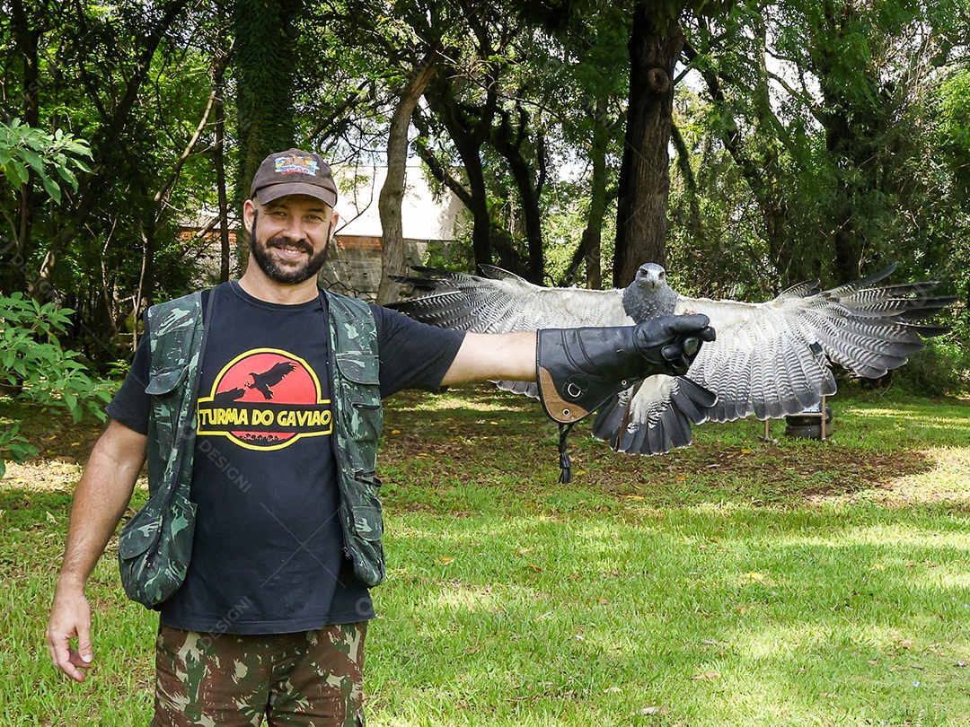 Homem jovem sobre campo verde com seu animal de estimação águia