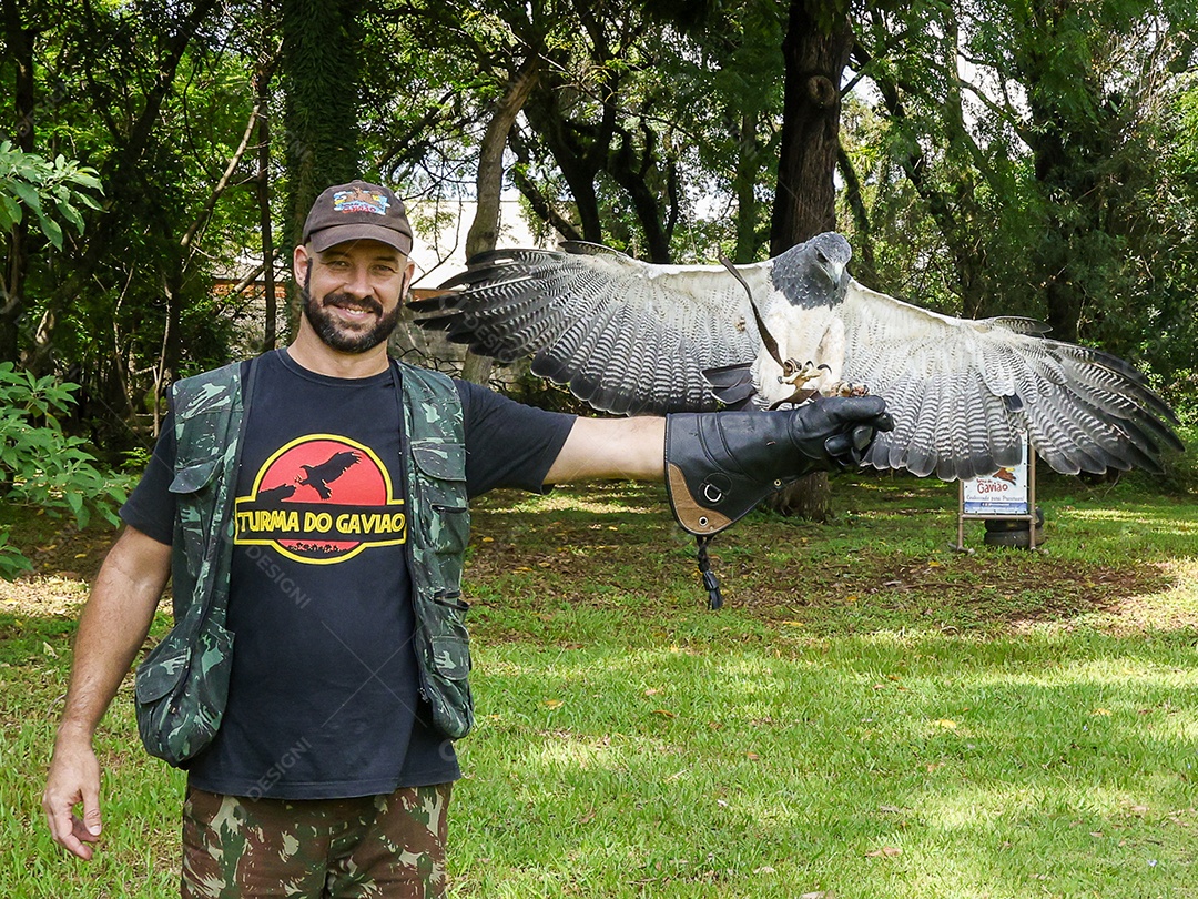 Homem jovem sobre campo verde com seu animal de estimação águia