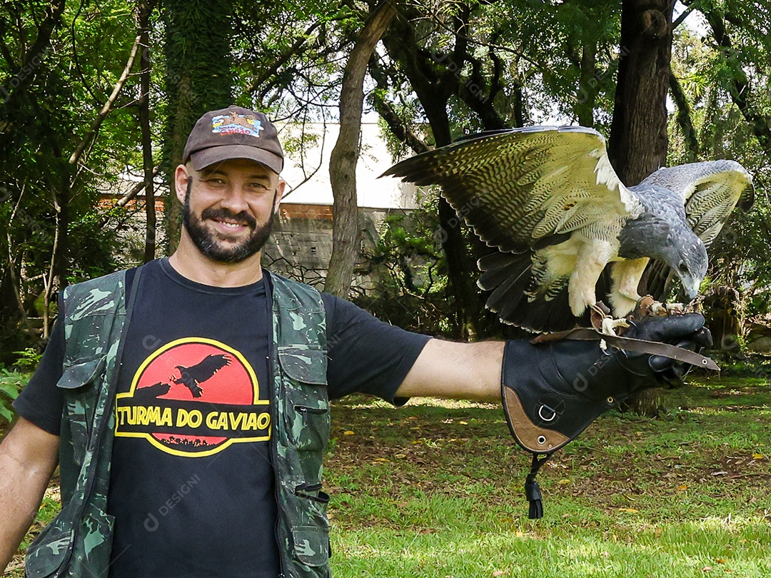 Homem jovem sobre campo verde com seu animal de estimação águia