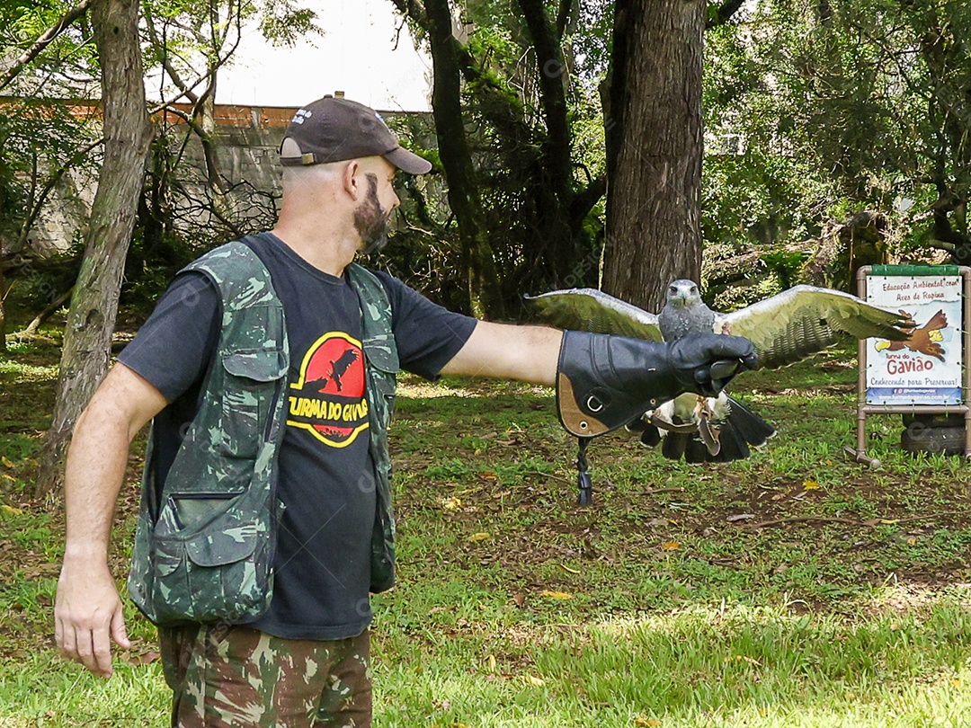 Homem jovem sobre campo verde com seu animal de estimação águia