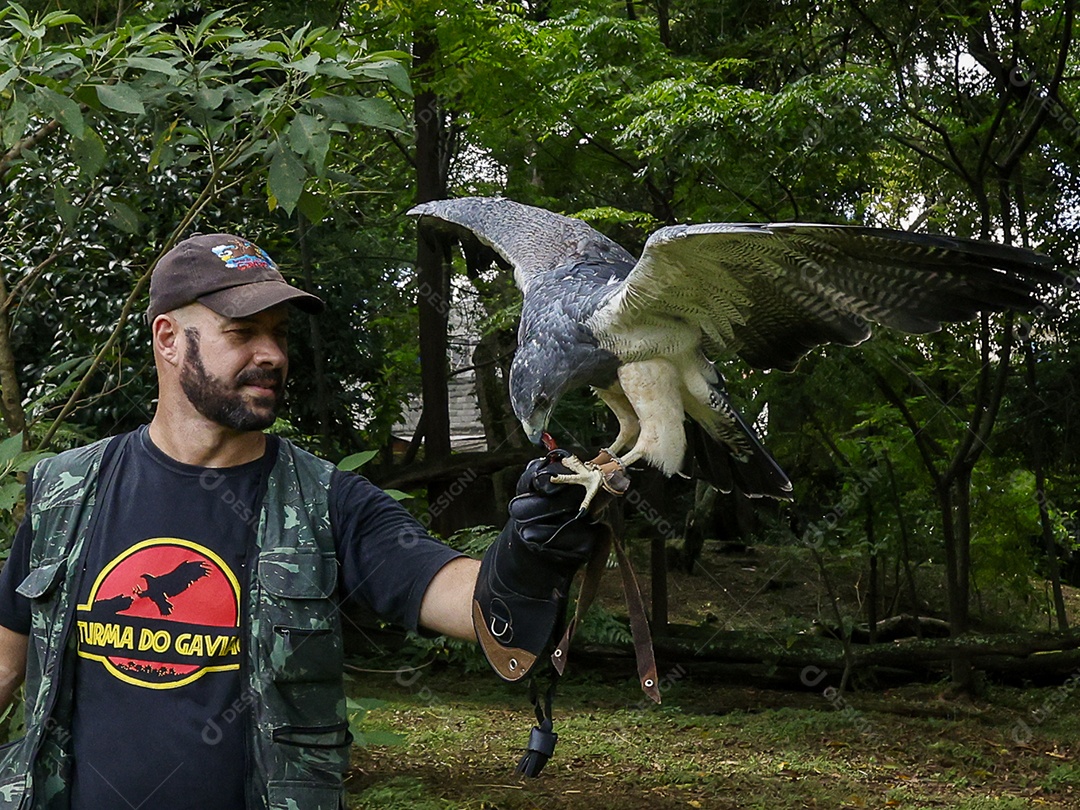 Homem jovem sobre campo verde com seu animal de estimação águia