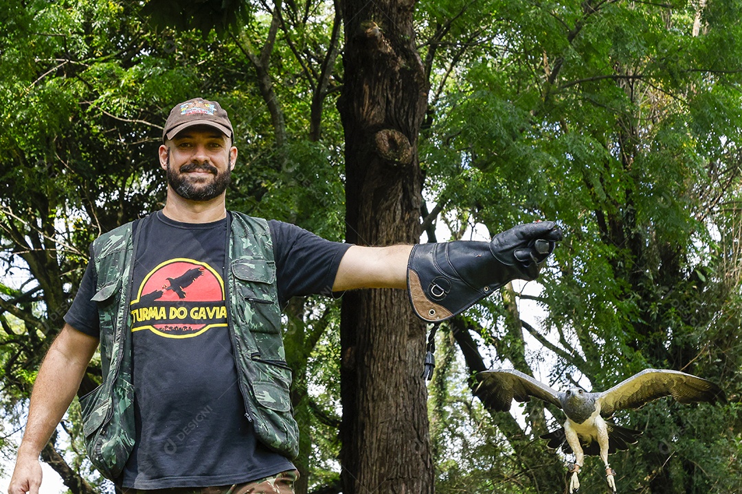Homem jovem sobre campo verde com seu animal de estimação águia