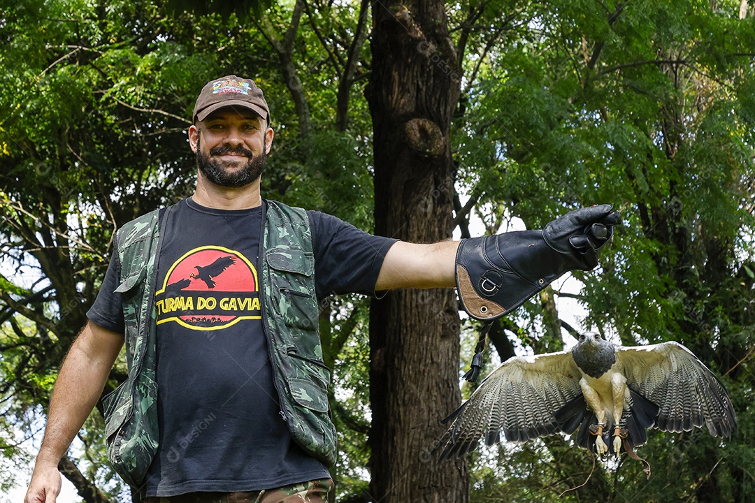 Homem jovem sobre campo verde com seu animal de estimação águia