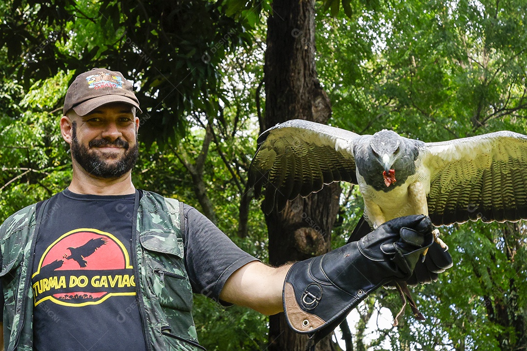 Homem jovem sobre campo verde com seu animal de estimação águia