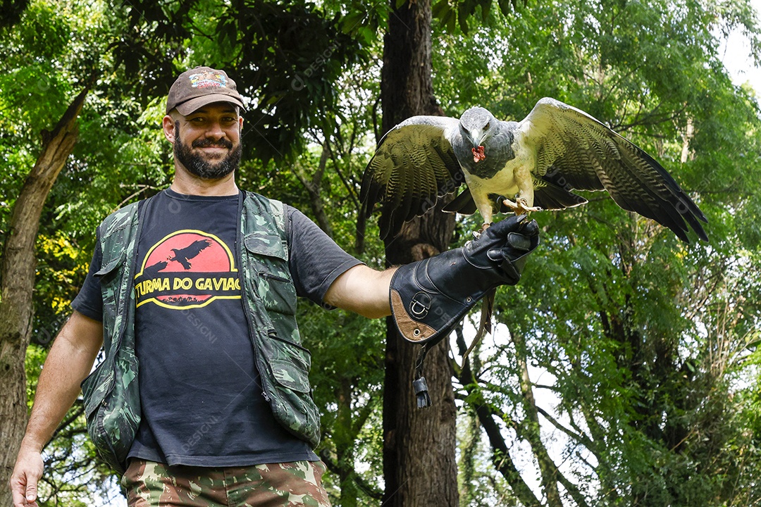 Homem jovem sobre campo verde com seu animal de estimação águia