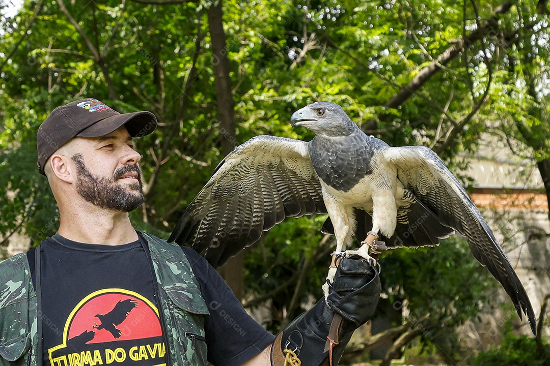 Homem jovem sobre campo verde com seu animal de estimação águia