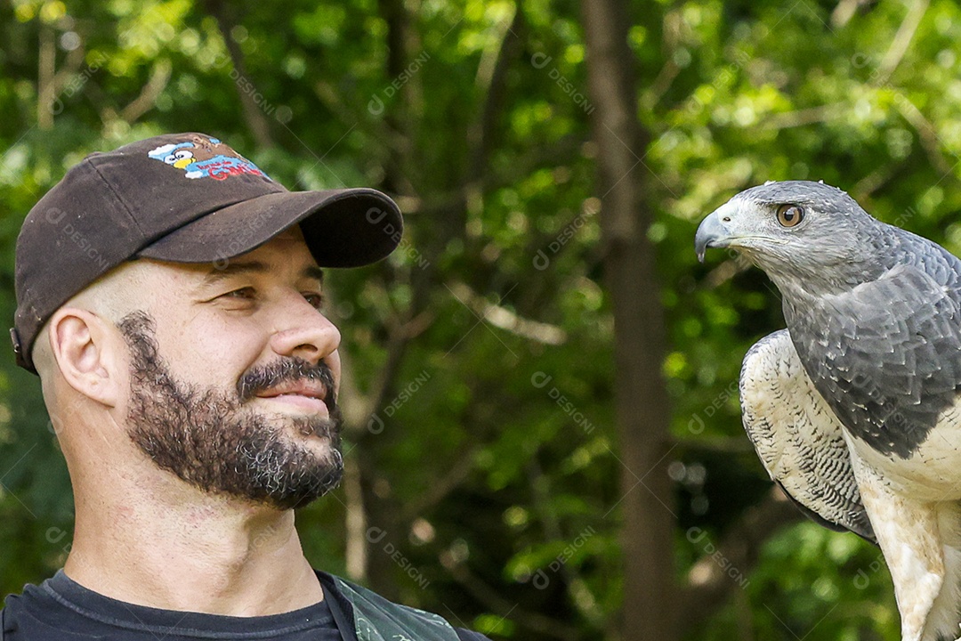 Homem jovem sobre campo verde com seu animal de estimação águia
