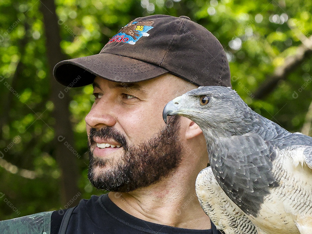 Homem jovem sobre campo verde com seu animal de estimação águia